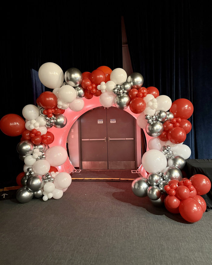 Red, white and silver balloon garland framing a round arch entrance