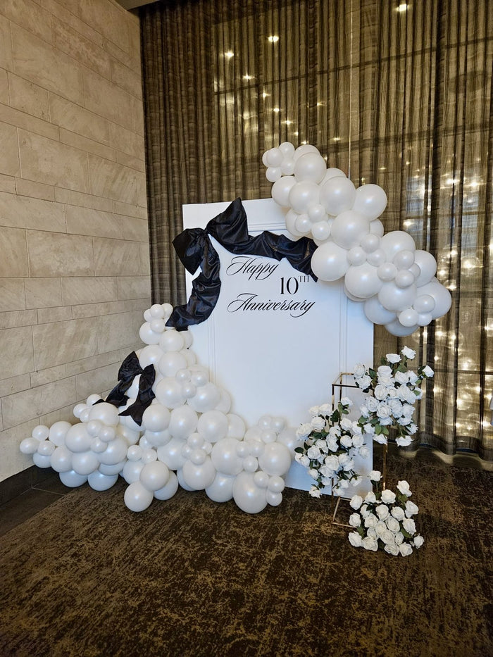 White balloon backdrop with black satin bows for a 10th anniversary celebration