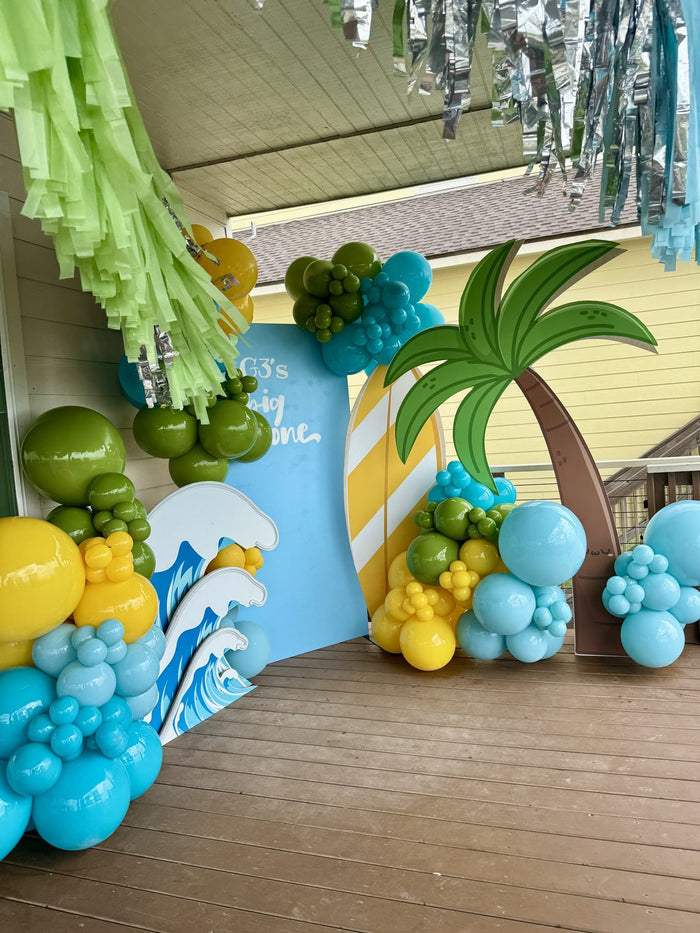 Surf themed first birthday balloon backdrop with palm tree and wave cutouts
