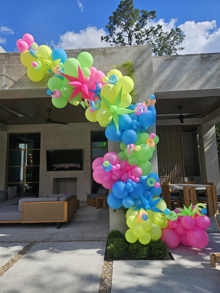 Bright tropical balloon garland by a pool at a Houston backyard party