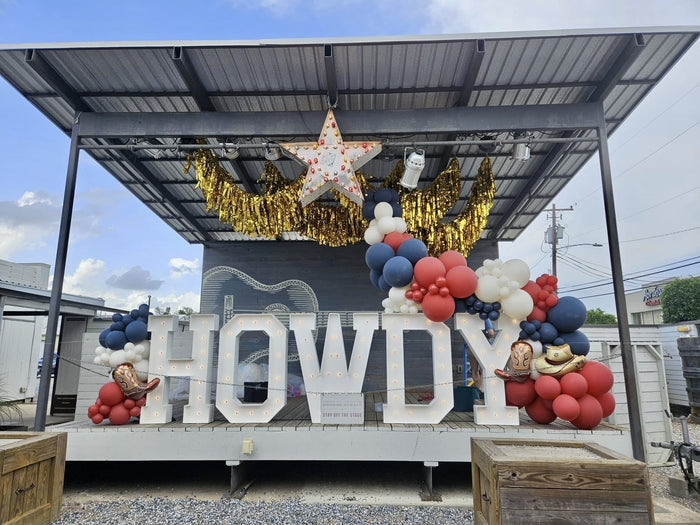 HOWDY light-up marquee letters with western balloon decor at a Houston event