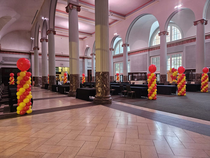 Red and yellow balloon columns lining a large event hall